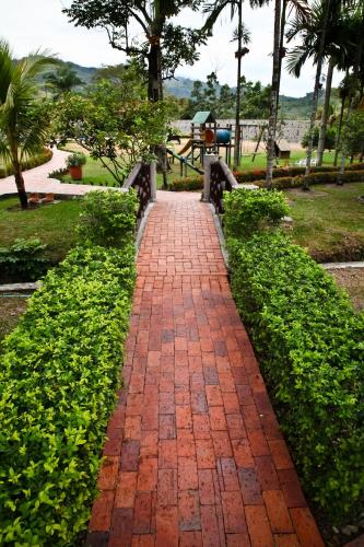 a red brick path in a park with green bushes at Hotel Boutique Villas de San Sebastián in Villavicencio