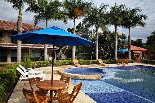 a table with an umbrella next to a swimming pool at Hotel Boutique Villas de San Sebastián in Villavicencio
