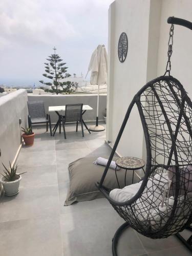 a swing chair sitting on top of a balcony at The Muses of Santorini Private Jacuzzi Suites in Vóthon