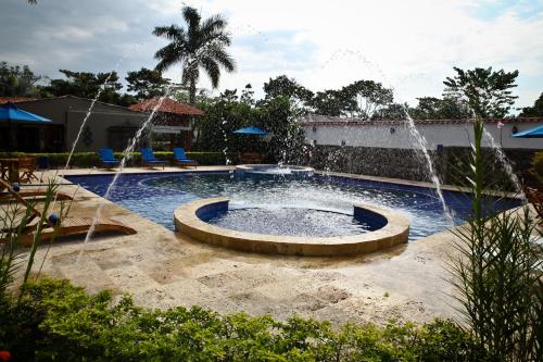 a swimming pool with a fountain in a yard at Hotel Boutique Villas de San Sebastián in Villavicencio