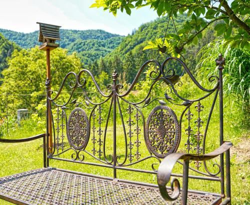a wrought iron bench with a view of the mountains at Emerald Bell Cottage - Smaragdni Zvonček in Gomilsko