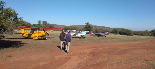 two men walking towards two planes in a field at Tranquillity Day Spa & Lodge in Baviaanspoort