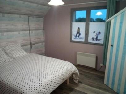 1 dormitorio con 1 cama y 2 fotos de personas esquiando en Chambre d’hôte, en Saint-Valery-sur-Somme