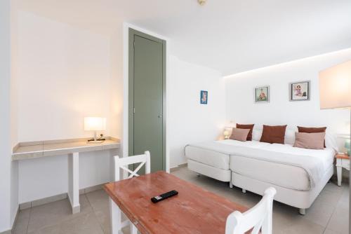 a bedroom with a bed and a desk and a table at Guya Wave Hotel in Cala Ratjada