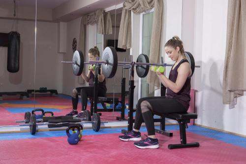 a woman sitting in a chair in a gym with weights at Alphaus Aparthotel in Pertisau