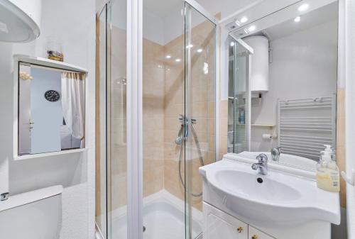 ein weißes Bad mit einer Dusche und einem Waschbecken in der Unterkunft Sea Blue - Appt à 1km de la plage in Villers-sur-Mer