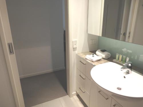 a bathroom with a white sink and a shower at AKOM AT Docklands in Melbourne