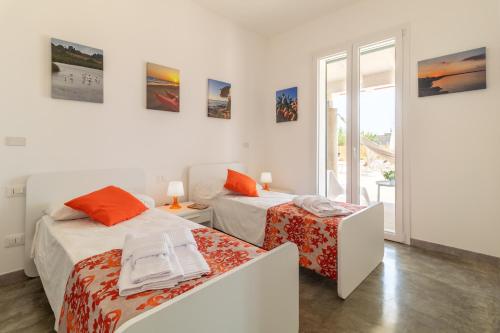 two beds in a white room with a window at Villa melograno in Ispica