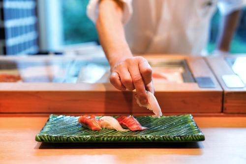 a person is preparing sushi on a plate at The Prince Park Tower Tokyo in Tokyo