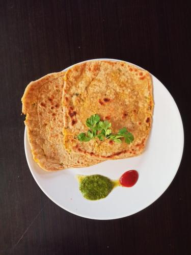 a white plate with a piece of pizza and a pickle at Bodhidham Yoga retreat Ashram in Pokhara