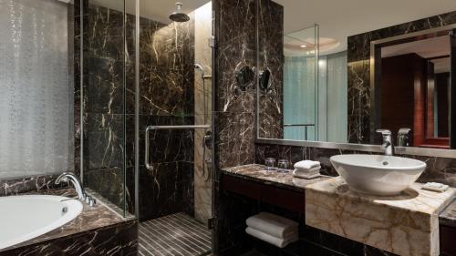 Sheraton Shunde Hotel في شوند: حمام مع حوض ومغسلة ودش
