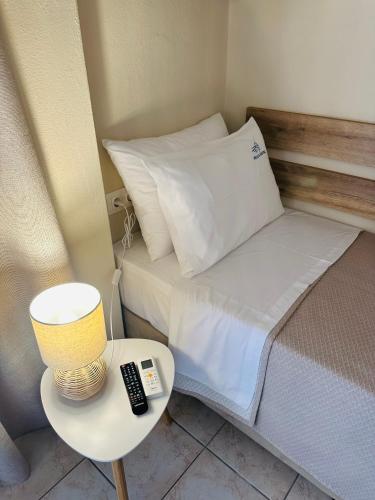 a bed with a lamp and a remote control on a table at Pella Hotel - new in Neos Marmaras