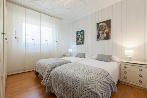 a white bedroom with two beds and a dresser at Cal Ramon con piscina in Rubí