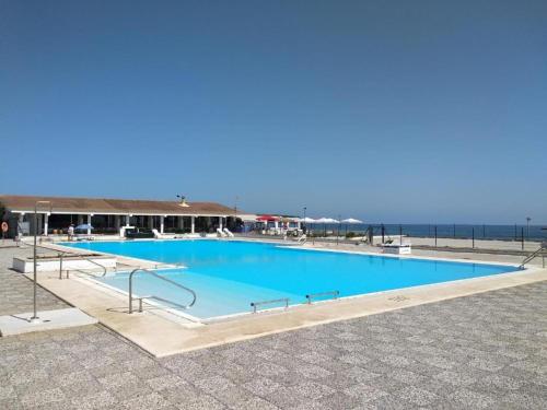 a large blue swimming pool next to the ocean at Caños de Meca Apartamento frente al mar in Los Caños de Meca
