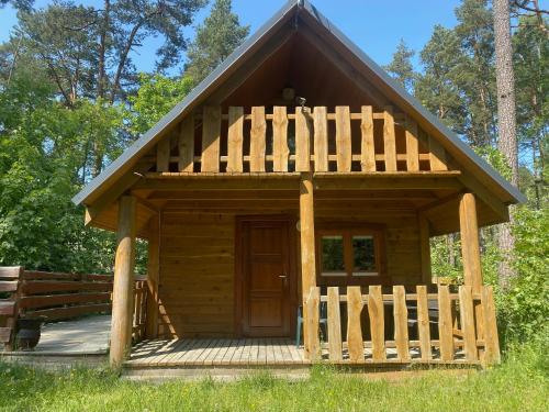 Cabaña de madera con porche y valla de madera en Domki Pod Sosnami, en Stegna