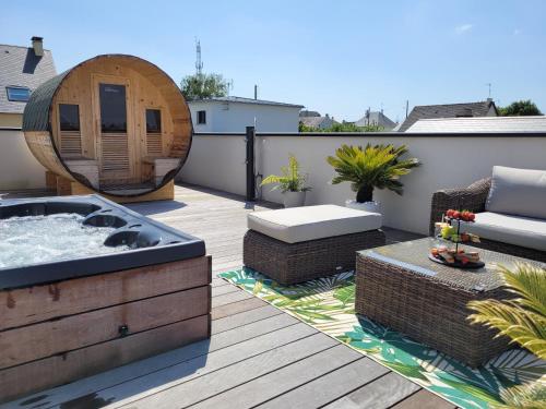 un patio con bañera de hidromasaje en una terraza en La Villa Thelma 5 étoiles, piscine, sauna et jacuzzi en Granville