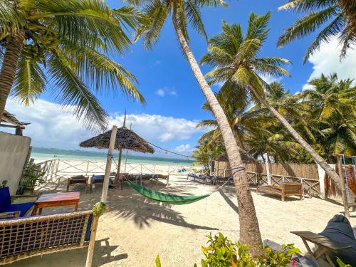 una hamaca en una playa con palmeras y el océano en The African Paradise Beach Hotel en Bwejuu