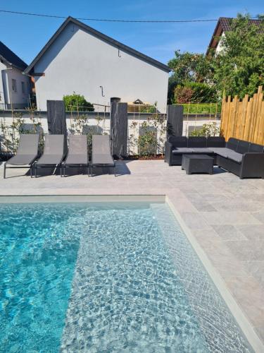 Logement privé dans une Villa avec piscine في Dalhunden: مسبح مع كراسي وكراسي بجوار منزل