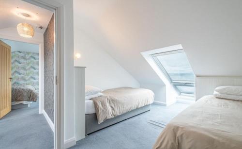 Promenade Apartment Panoramic sea Views Portstewart في بورتستيوارت: غرفة نوم بيضاء بسريرين ونافذة