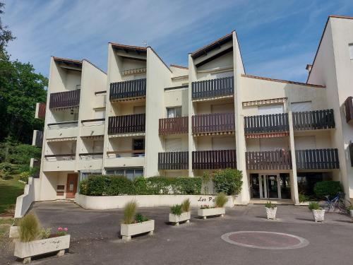un grand bâtiment blanc avec des plantes dans un parking dans l'établissement Joli studio - 2 pas de la mer et du centre, à Saint-Georges-de-Didonne