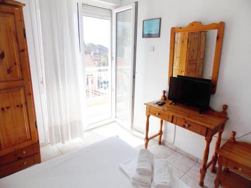 a living room with a television and a mirror at Hotel Sgouridis in Limenaria