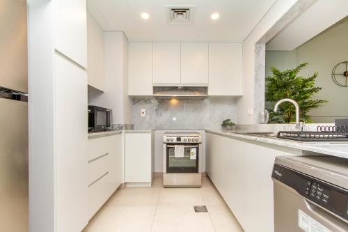 a kitchen with white cabinets and a stove at Ultimate Stay - Luxury 2BR Apartment with Iconic Burj Al Arab View from the Swimming Pool in Dubai