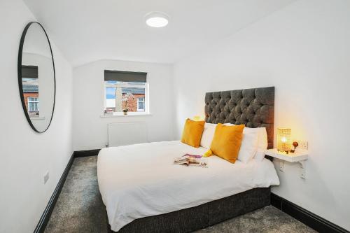 ein Schlafzimmer mit einem großen weißen Bett mit orangefarbenen Kissen in der Unterkunft TYME Coastal Retreats - 1 and 2 Bedroom in Cleethorpes