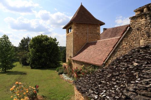 a brick building with a tower on top of a yard at les Tours de Bombel in Saint-Amand-de-Coly