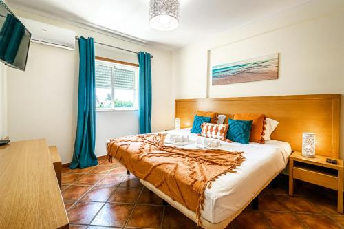 um quarto com uma cama grande e cortinas azuis em BeGuest Jardins Vale Parra Apartment em Albufeira