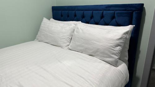a bed with white pillows and a blue headboard at Homestay in Walsall in Walsall