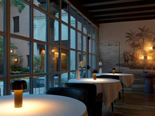 ヴェネツィアにあるパラッツォ ヴェーナルト ラグジュアリー ホテルのテーブルと椅子、大きな窓のあるレストラン