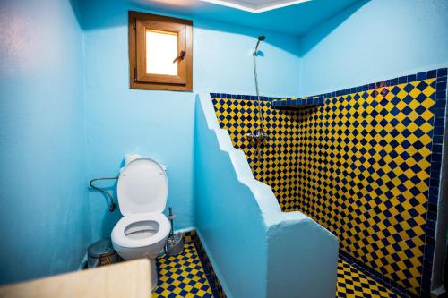 a blue bathroom with a toilet and a checkered wall at Riad Merzouga Dunes in Merzouga