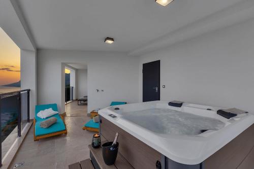 - une grande baignoire dans une pièce avec des chaises bleues dans l'établissement Premium Serenitas Ponti Apartment, à Brela