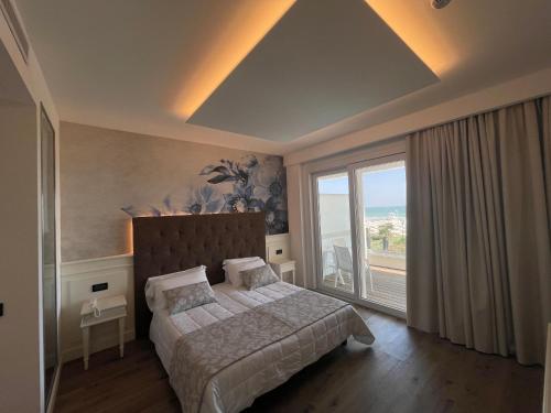 een slaapkamer met een bed en een groot raam bij Park Hotel Cellini in Lido di Jesolo