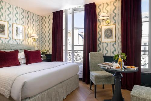 um quarto de hotel com uma cama, uma mesa e uma janela em Hotel du Champ de Mars em Paris