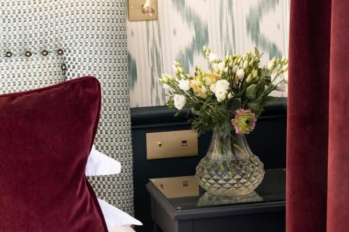 a vase of flowers on a table in a bedroom at Hotel du Champ de Mars in Paris