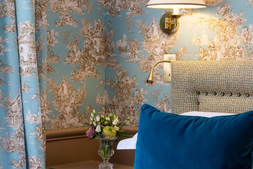 Un dormitorio con una almohada azul y una pared con papel pintado en Hotel du Champ de Mars, en París