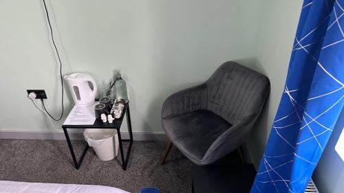 a bedroom with a chair and a table with a lamp at Homestay in Walsall in Walsall