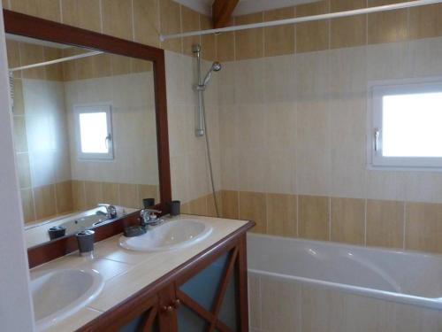 ein Badezimmer mit zwei Waschbecken, einer Badewanne und einem Spiegel in der Unterkunft Maison L'Aiguillon-sur-Vie, 4 pièces, 6 personnes - FR-1-224-671 in Saint-Révérend