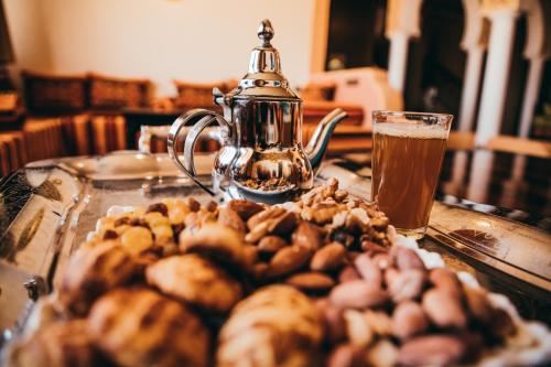 a glass table with a tea kettle and a pile of nuts at Riad Merzouga Dunes in Merzouga