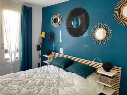 une chambre avec un mur bleu avec un lit et des miroirs dans l'établissement EOLE, Idéalement situé sur le port de St Martin de Re, à Saint-Martin-de-Ré