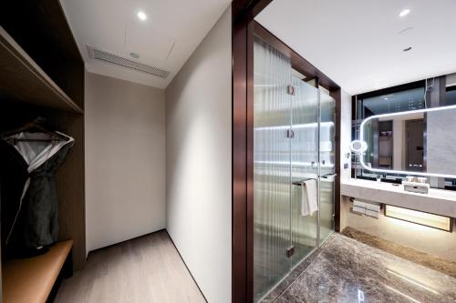 La salle de bains est pourvue d'une douche et d'une porte en verre. dans l'établissement UrCove by HYATT Shenzhen Luohu, à Shenzhen