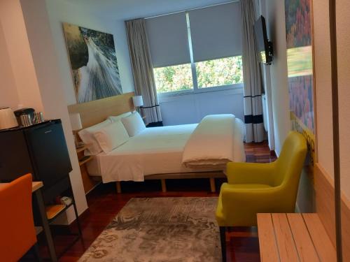 a bedroom with a bed and a chair and a window at Suite Bilbao Arena con plaza de garaje in Bilbao