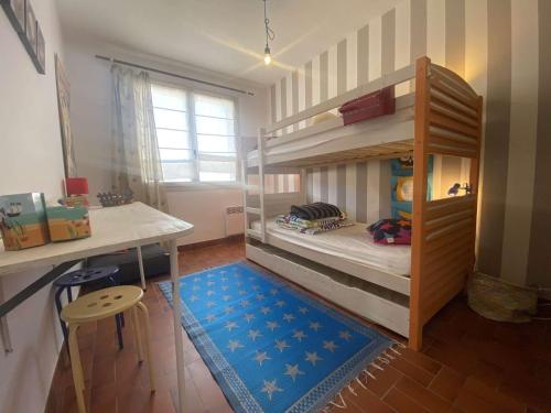 Cette chambre comprend 2 lits superposés, une table et un tabouret. dans l'établissement Maison 6 pers. avec jardin et terrasse, proche plage et forêt, animaux admis, ménage inclus - FR-1-246A-183, à Saint-Georges-dʼOléron