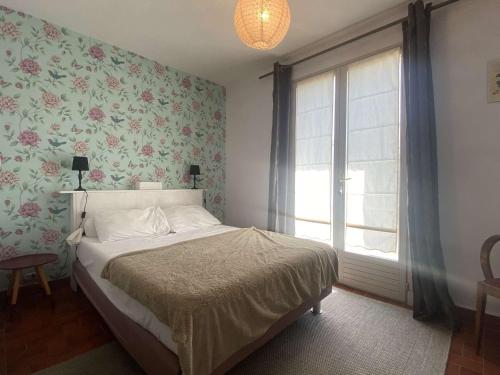 een slaapkamer met een bed en een raam met bloemenbehang bij Maison Saint-Georges-d'Oléron, 5 pièces, 6 personnes - FR-1-246A-183 in Saint-Georges-dʼOléron