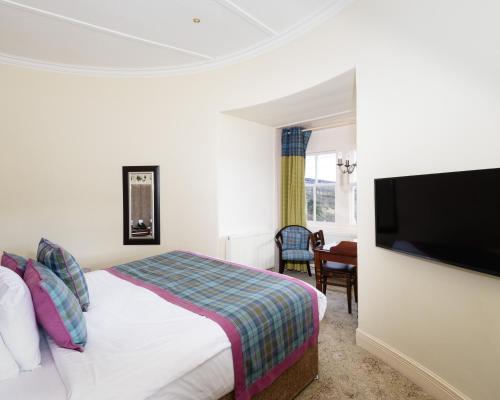 a hotel room with a bed and a flat screen tv at The Atholl Palace in Pitlochry