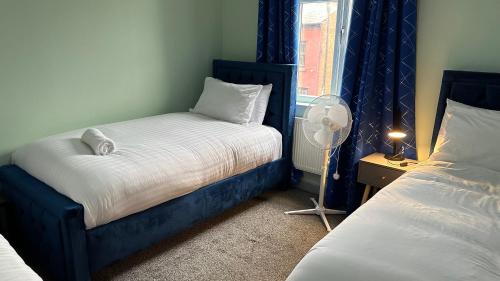 een slaapkamer met 2 bedden, een ventilator en een raam bij Homestay in Walsall in Walsall