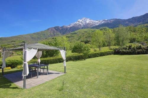 a gazebo in a field with mountains in the background at Legnoncino Holiday Home- Lake Como in Colico