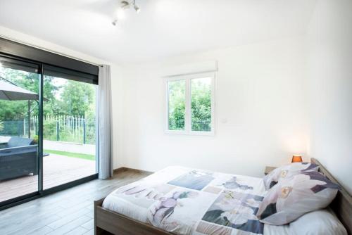 um quarto com uma cama e uma porta de vidro deslizante em Maison individuelle avec piscine privative. em Saint-Médard-en-Jalles