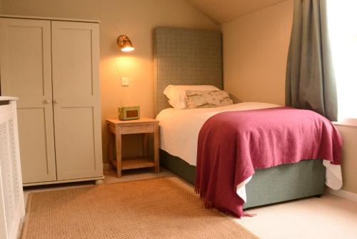 a small bedroom with a bed with a pink blanket at Scourie Hotel in Scourie